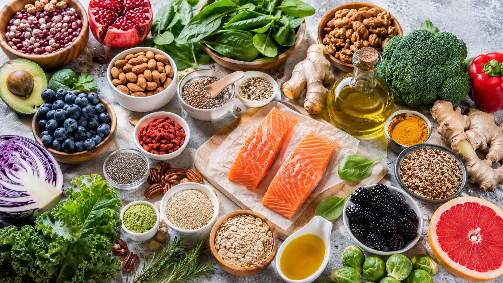 An overhead spread of anti-inflammatory whole foods — wild salmon, blueberries, leafy greens, nuts, seeds, avocado, turmeric, ginger, and olive oil.