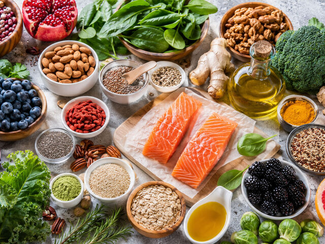 An overhead spread of anti-inflammatory whole foods — salmon, blueberries, greens, nuts, turmeric, and ginger.