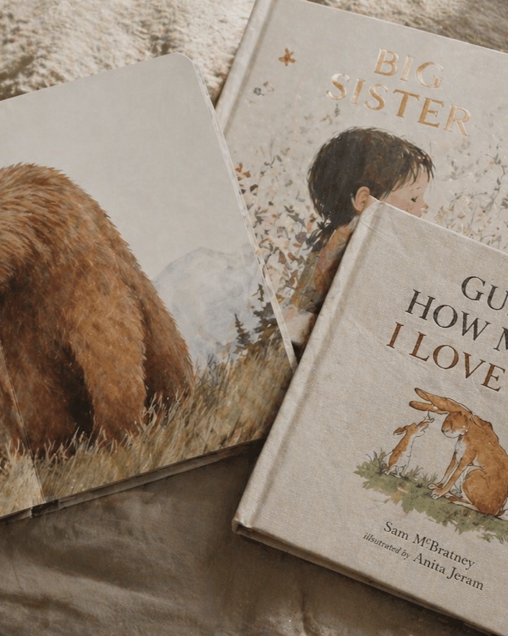 Four well-loved children's picture books arranged on soft linen in warm natural light