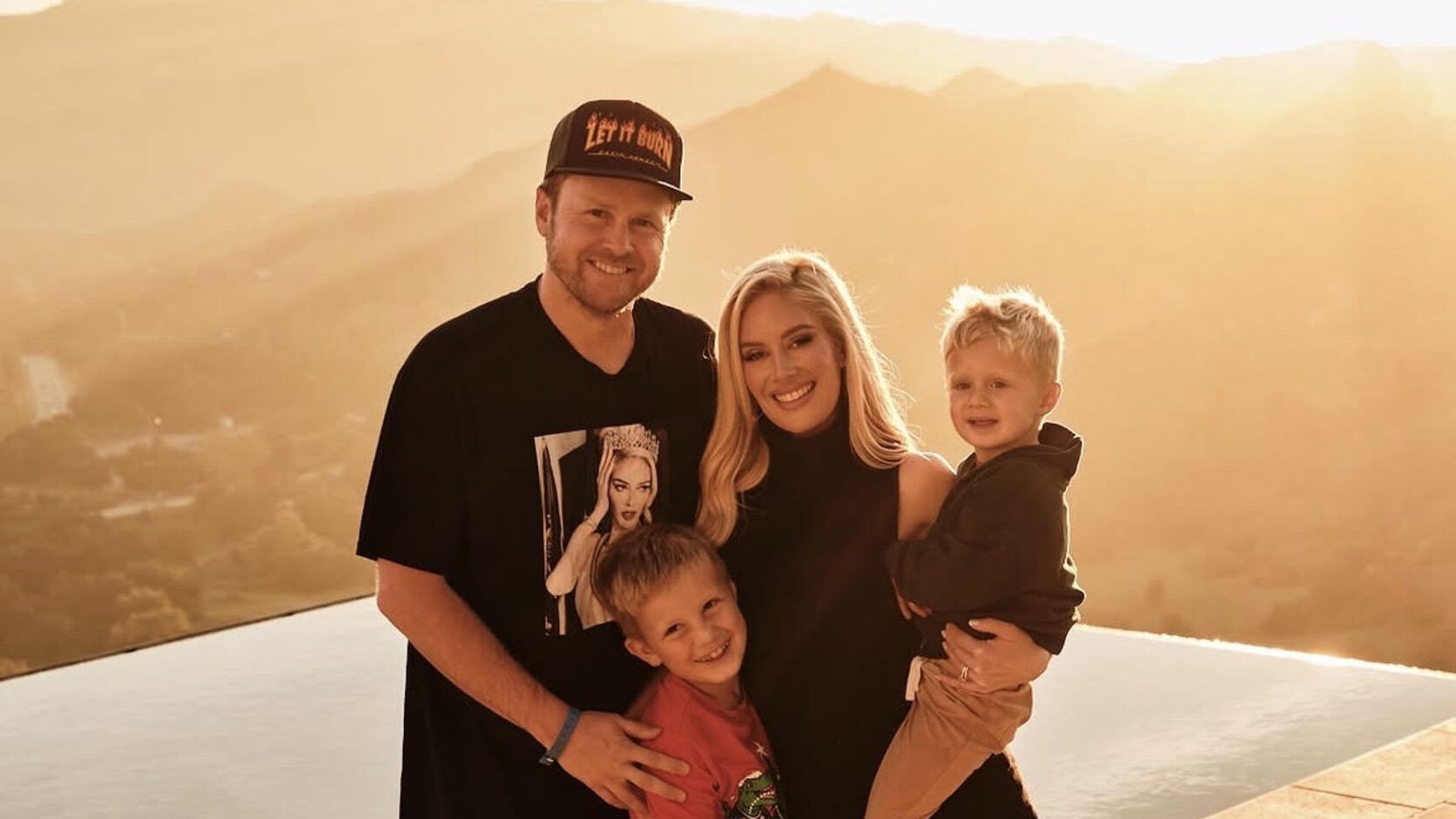 Heidi Montag, Spencer Pratt, and their two young sons stand together beside an infinity pool at golden hour, the hills glowing behind them.