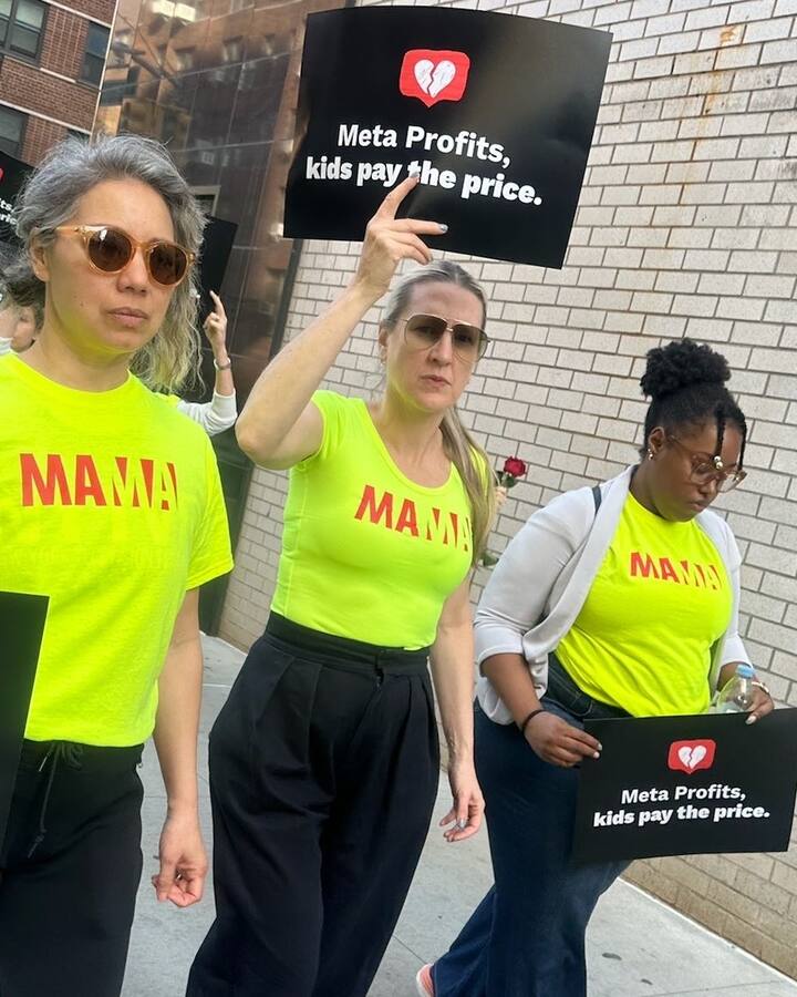 Mothers in neon yellow MAMA t-shirts march down a city sidewalk holding black signs that read "Meta Profits, kids pay the price."