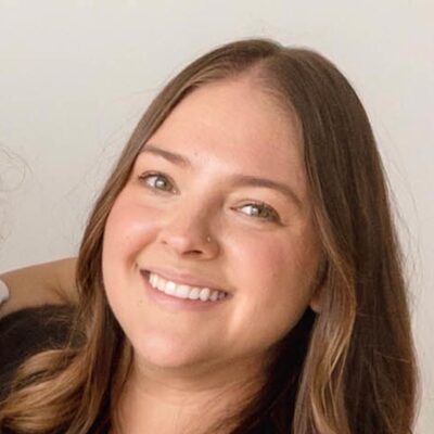Headshot of Sam Blay, a Momé contributor, smiling in a brown sweater.