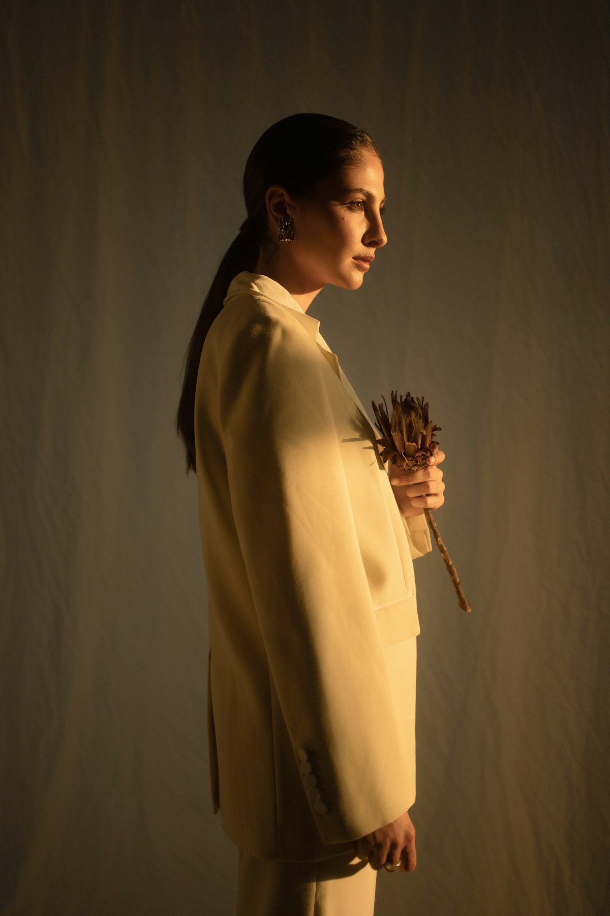 A young woman in a soft yellow dress in an editorial portrait, warm natural light