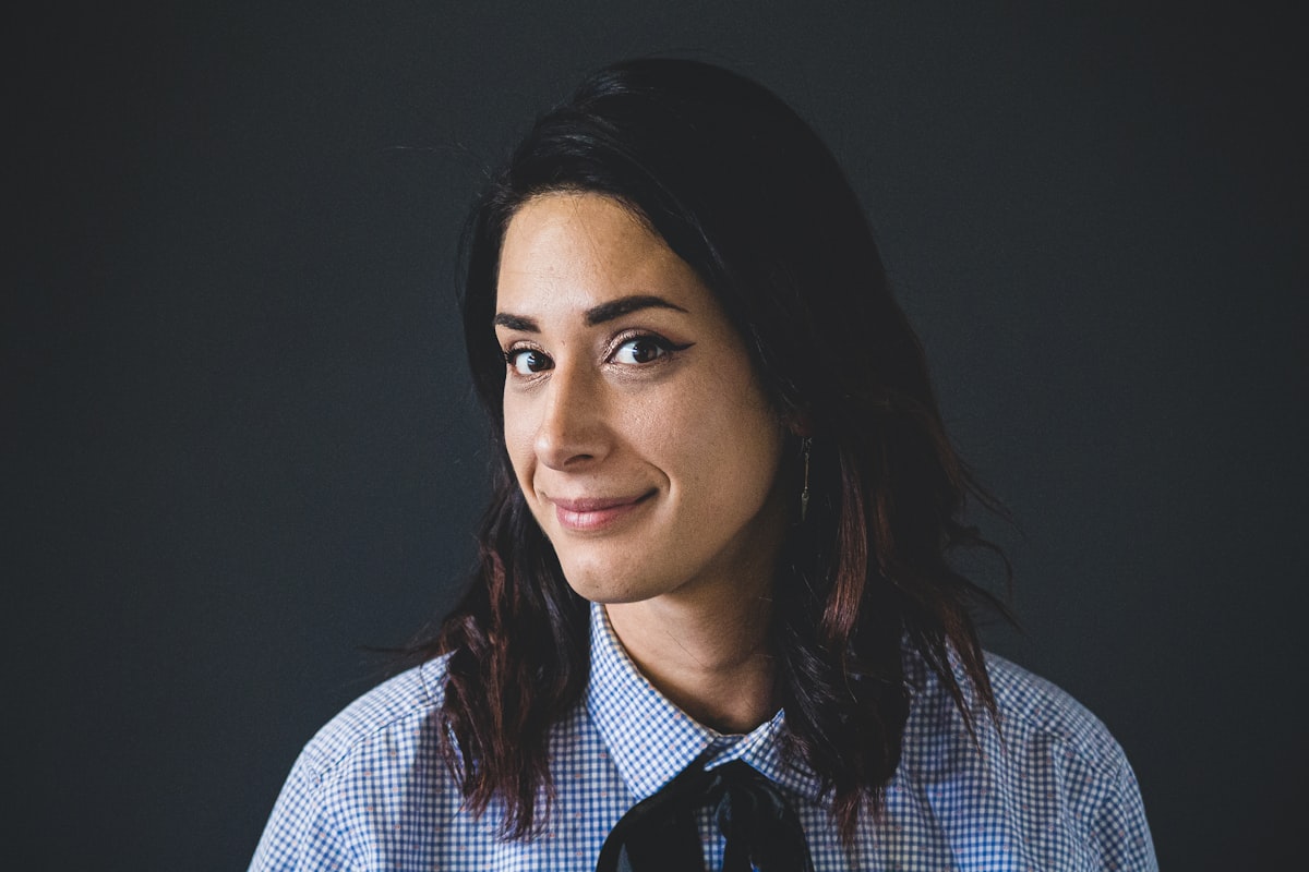 An editorial portrait of a smiling woman against a dark backdrop