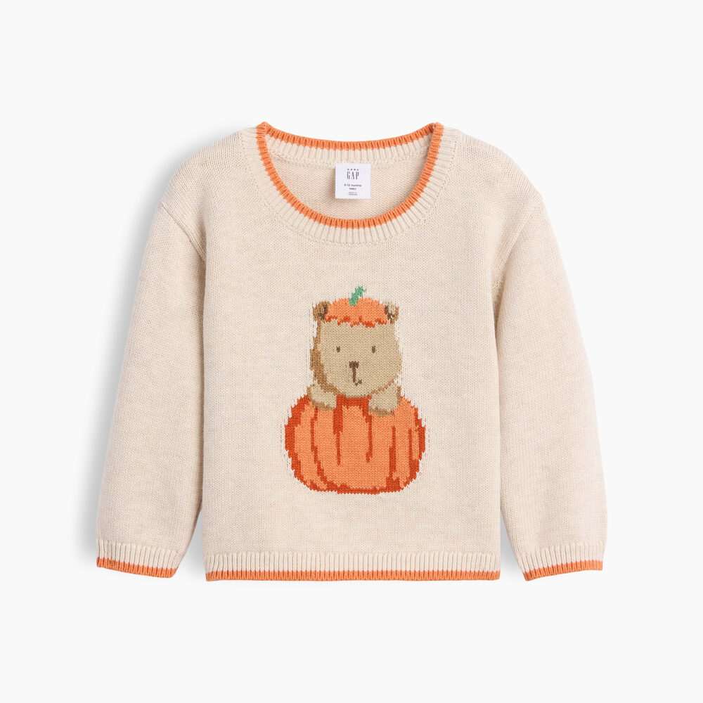 An oatmeal-heather knit baby sweater with orange-tipped crewneck, cuffs and hem, and a knitted Brannan Bear in a pumpkin hat peeking out of a big orange pumpkin on the front.
