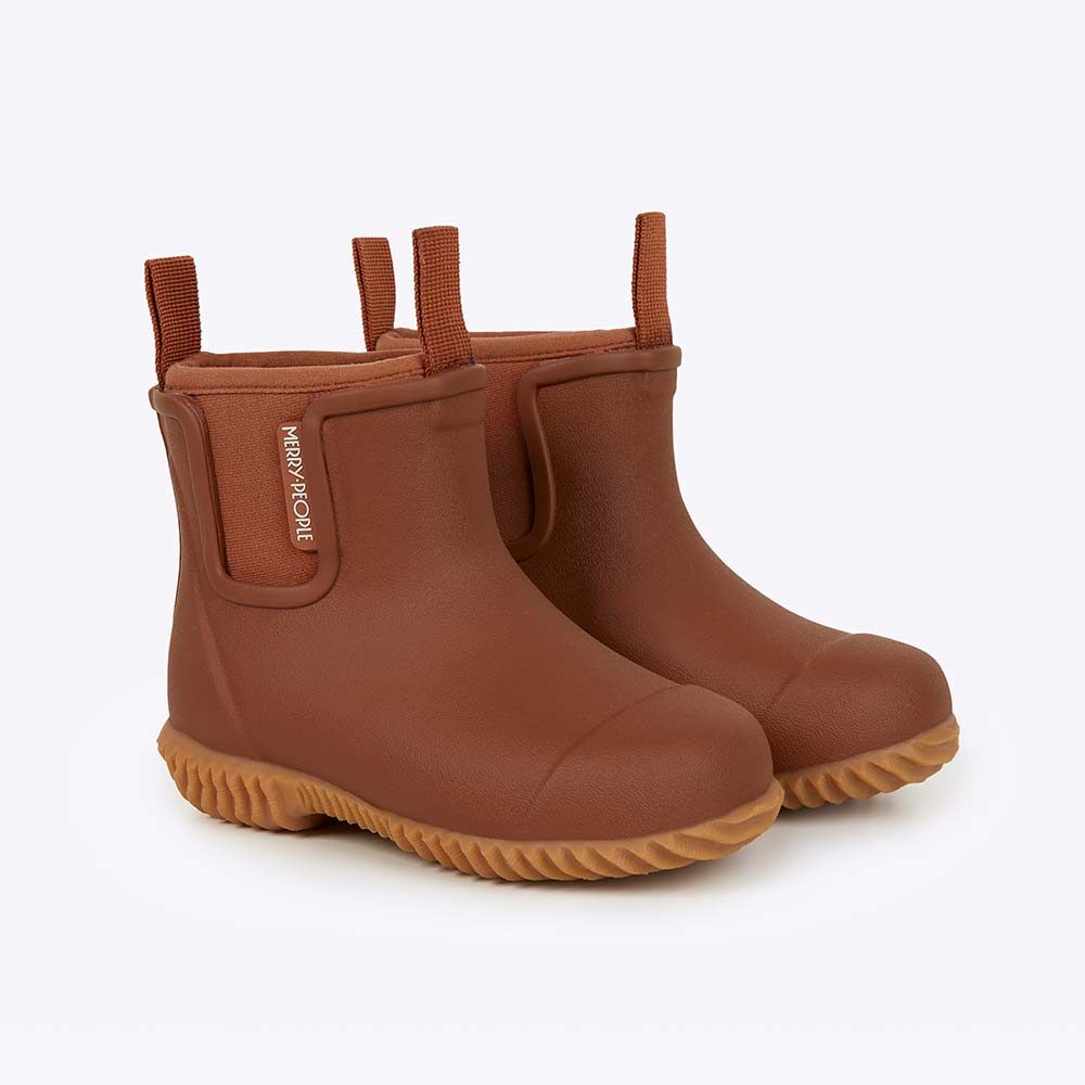 A pair of rust-brown Merry People Bobbi Kids rain boots, ankle height with matching pull tabs, side panels and a chunky ridged tan sole, on a white background.