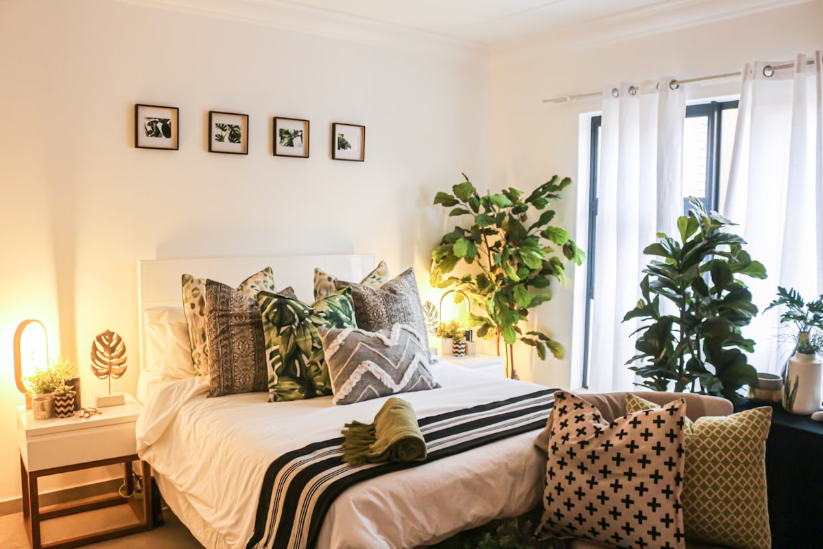 A serene cream-toned bedroom corner with a potted plant and ambient morning light