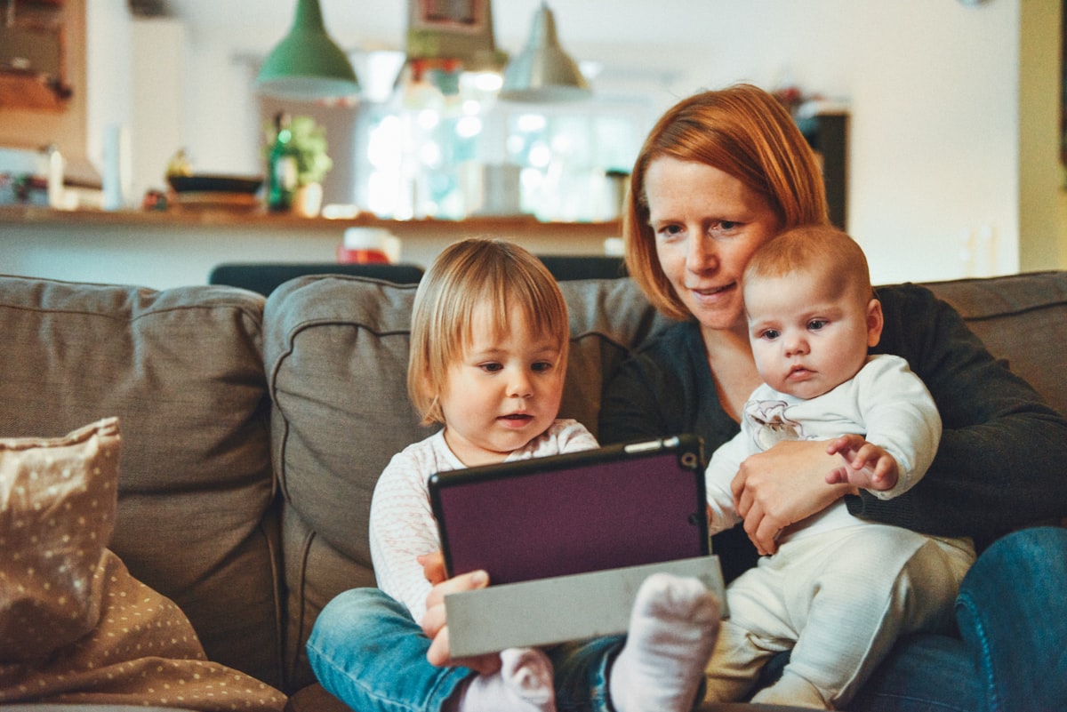 A mother with two young children, sitting on a couch in soft lamplight